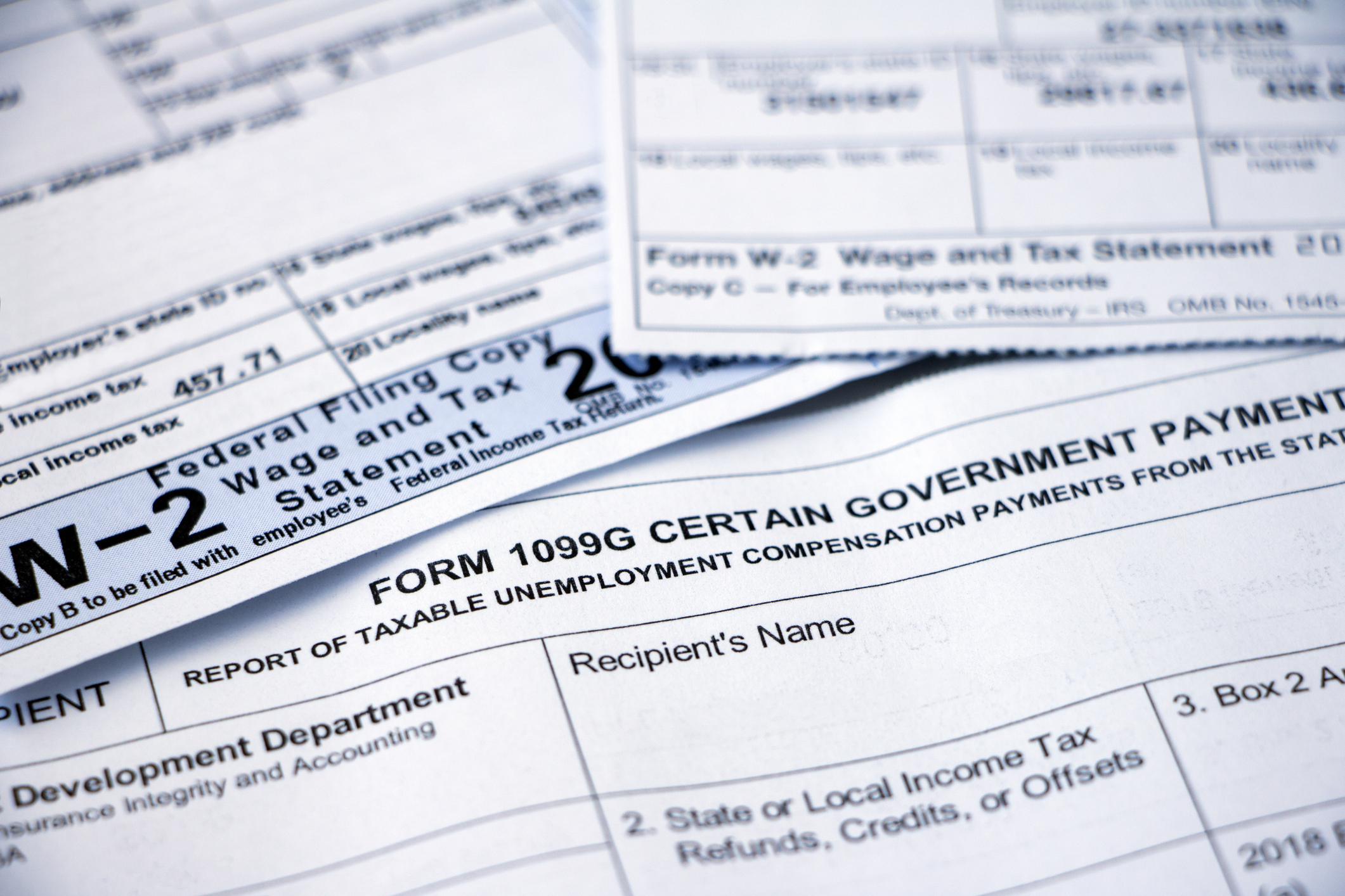 A close view of neatly stacked tax forms, a notebook, and a laptop on a kitchen table as a parent organizes paperwork for college financial aid