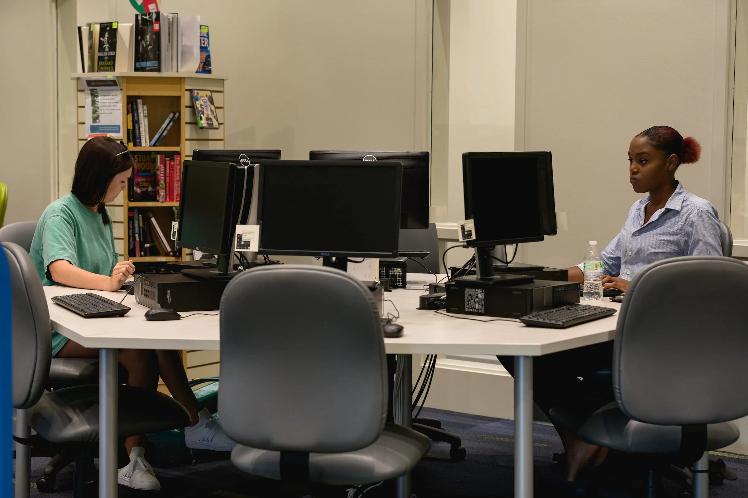 A college student seated at a computer in a quiet testing room, focusing on a proctored exam screen