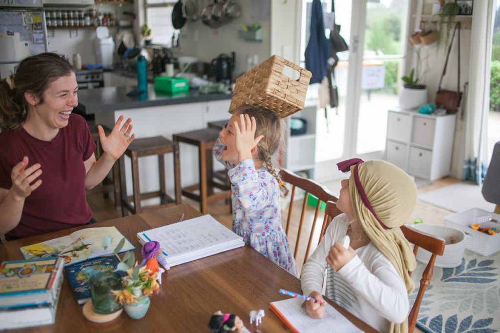A parent and child sitting at a kitchen table with open books and a simple planner, working calmly in natural morning light