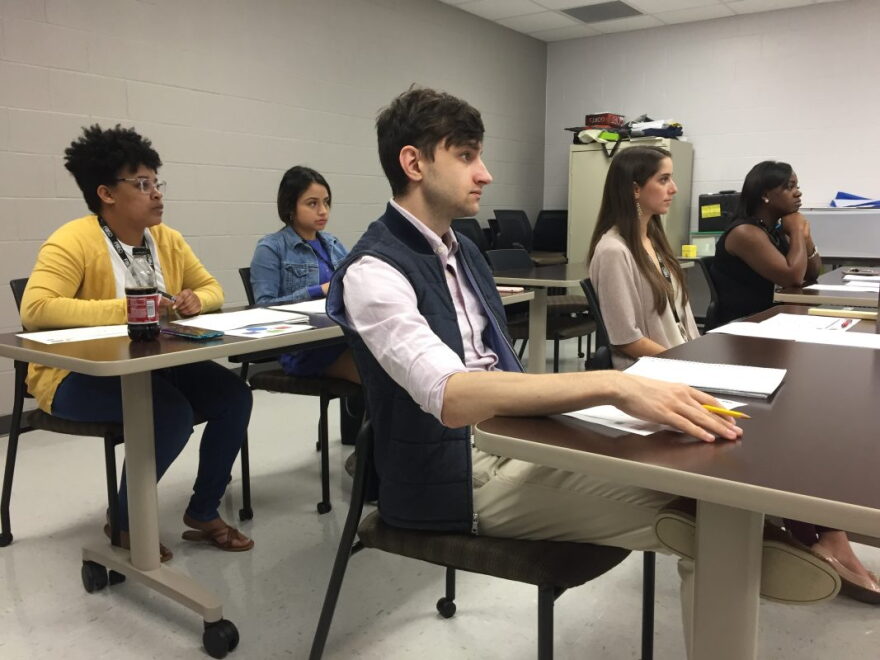 A school psychologist and special education teacher sitting with a parent at a table while reviewing student reports and notes